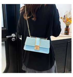 Close-up of light blue chain handbag with pink glitter flap and gold metal twist lock
