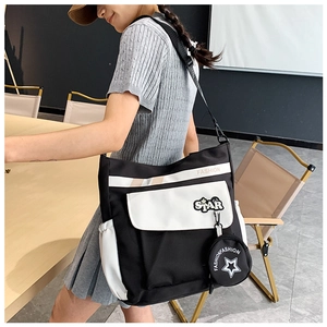 Détail d'un sac bandoulière en toile noir et blanc avec patch étoile et petit porte-monnaie