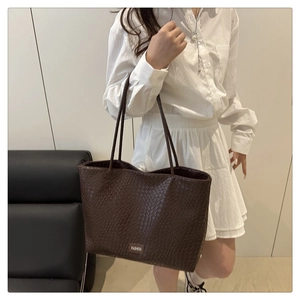 Close-up of dark brown woven texture tote bag with a small decorative fashion label