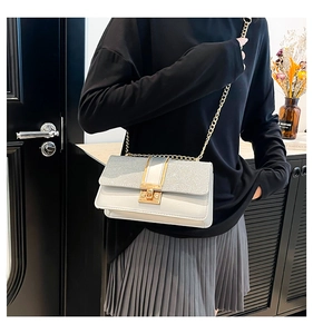 Close-up of a stylish white crossbody bag with glitter flap and gold metal lock detail