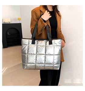 Bolso tote acolchado plateado con asas negras combinado con abrigo de invierno