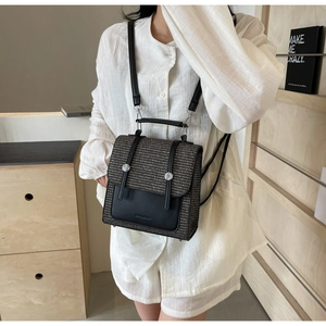Detail view of woven grey fabric backpack with black leather straps and front pocket