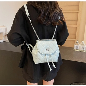 Rückansicht eines minzgrünen gesteppten Mini-Rucksacks mit silbernen Kettenriemen am Model