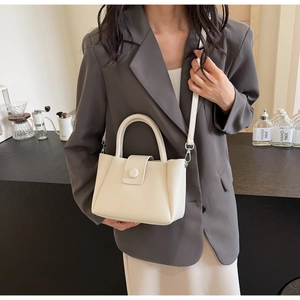 Detailed shot of beige lychee pattern handbag with adjustable leather shoulder strap
