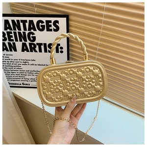 Detalle de bolso de fiesta dorado con grabados de corazones y asa metálica trenzada