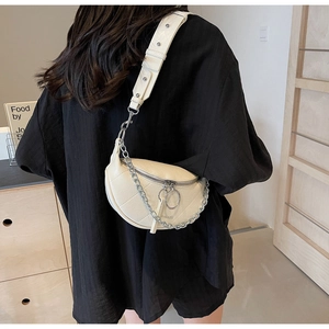 Close-up of cream leather crescent bag with quilted texture and silver chain strap