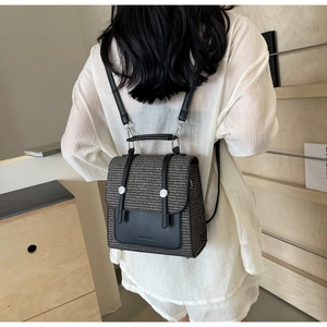 Detail view of woven straw backpack with black leather flap and silver buckle accents