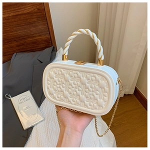 Detalle del bolso de caja blanco con relieve floral 3D y elegante cierre metálico dorado