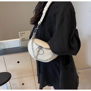 Detail of a beige quilted saddle bag with silver chain strap and metal ring zipper