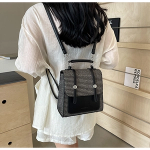 Detail of grey woven backpack with black leather flap on a model wearing white shirt