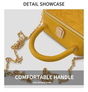 Detail of yellow box bag with floral relief, metal chain and sturdy leather handle