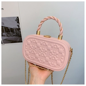 Detalle de bolso caja ovalado rosa con relieve de corazones y cierre dorado elegante