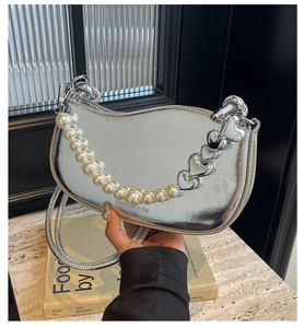 Detail of silver metallic crescent bag with pearl heart chain and sleek finish