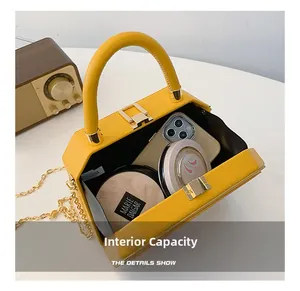 Macro view of interior capacity of the yellow box bag showing smartphone and cosmetics
