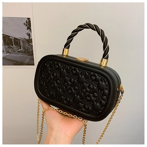 Detalle de bolso negro con textura de corazones y correa de cadena dorada fina