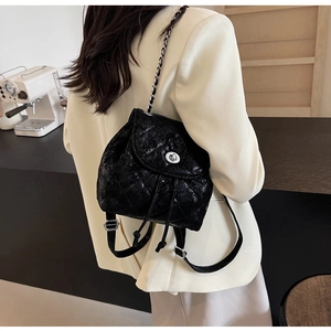 Detailansicht eines schwarzen Mini-Rucksacks mit Steppmuster und Kettenriemen