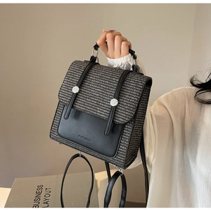 Detail of checkered woven backpack featuring black leather straps and silver buckles