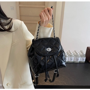 Detail eines schwarzen gesteppten Rucksacks mit silbernem Drehverschluss und Kettenriemen