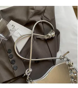 Silver underarm bag detail featuring a heart-shaped chain and smooth long shoulder strap