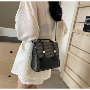 Detail shot of a retro woven crossbody bag with black leather trim and silver metal buckles