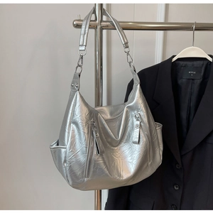 Detail van zilveren halvemaantas met metallic kreuktextuur en dubbele ritsen