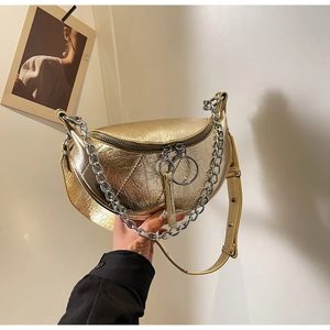 Close-up of golden crescent bag with metallic texture, silver chain, and ring zippers
