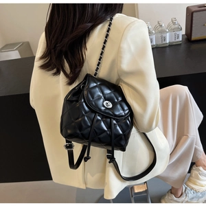 Nahaufnahme eines schwarzen gesteppten Lederrucksacks mit silbernen Ketten auf dem Modell