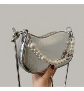 Detail of silver metallic handbag with pearl strap and heart pendant on a blazer