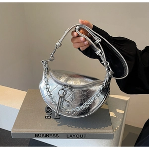 Detail of silver metallic dumpling bag featuring pleated texture and oversized ring zipper