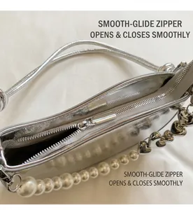 Detail of smooth top zipper and designer pearl heart chain on silver underarm bag