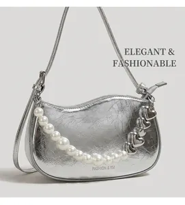 Detailed close-up of silver crescent bag featuring pearl and metal heart chain ornaments