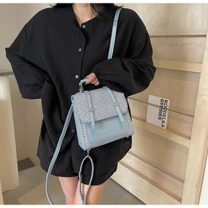 Detail of light blue woven texture and leather trim on a stylish women's backpack