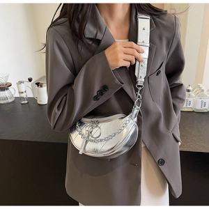 Close-up of silver crescent saddle bag with metallic chain and textured wide strap