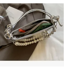 Detailed interior view of a silver metallic shoulder bag with pearl chain and inner zipper pocket