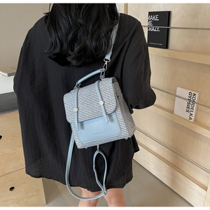 Detail of blue straw backpack with leather buckle and straps on a wooden shelf