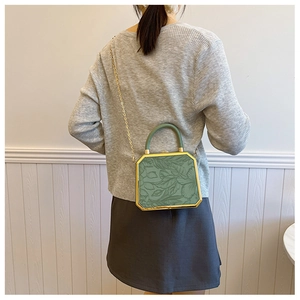 Detailed back view of green octagonal crossbody bag with embossed leaf patterns