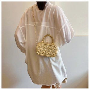 Bolso rígido dorado con corazones en relieve, asa retorcida y correa de cadena metálica