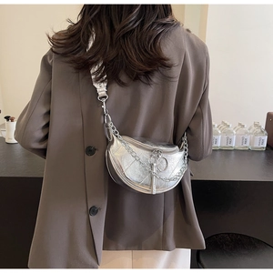 Detail of silver crescent saddle bag with metal chain strap and wide woven shoulder band