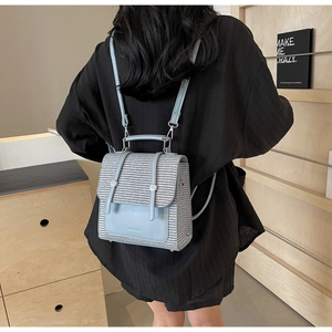 Detail of light blue straw backpack with woven texture and synthetic leather pocket