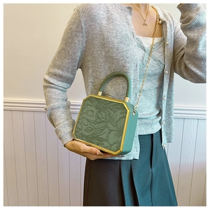 Detail of dark green octagonal box bag featuring 3D floral relief and gold metal frame