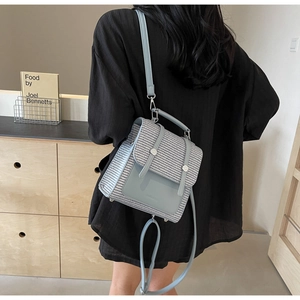 Detailed side view of light blue woven texture backpack with smooth leather accents