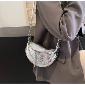 Detailed view of silver crescent bag with metallic pleated texture and chain detail
