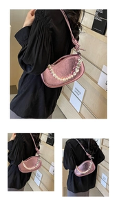 Close-up of bright pink metallic ruched baguette bag with pearls and heart pendant