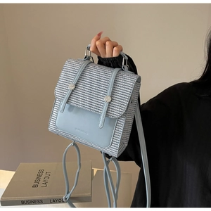 Detail of light blue straw woven backpack with silver hardware and top handle