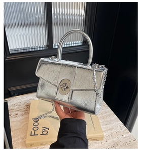 Macro view of silver crinkled texture handbag with a metallic finish and chain strap