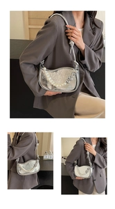 Detail of silver pleated leather bag featuring pearl and heart-shaped chain decor