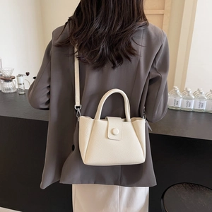 Sac seau en cuir blanc crème avec poignées et bandoulière dans un décor de studio