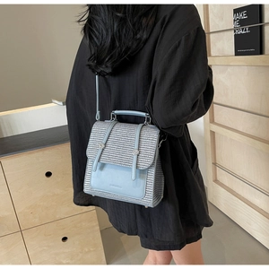 Detail of blue and grey houndstooth fabric texture and leather mini backpack straps