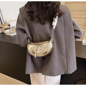 Detail of metallic gold crescent bag featuring pleated texture and silver chain strap