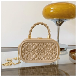 Detalle de bolso caja beige estructurado con diseño de corazones y correa de cadena dorada